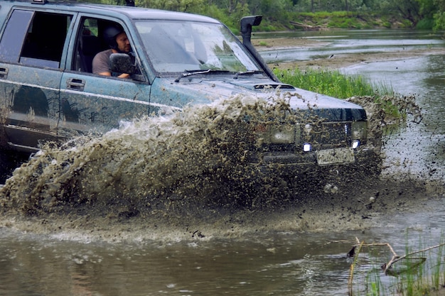 4x4 offroad car crosses a water barrier with splashes at high speed