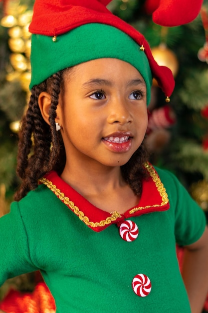 5-year-old Afro-Colombian Colombian Latino girl dressed as an elf next to the Christmas tree