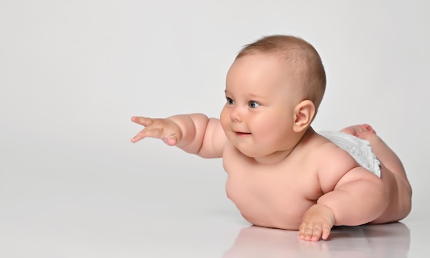 6 month old baby infant lies in one diaper on a light background