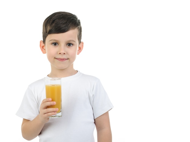 A 6-year-old boy in a white T-shirt holds a glass with citrus juice on a white background. Isolated background.