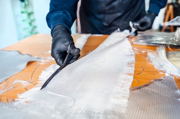 62 year old man cutting fiber with scissors in the workshop.