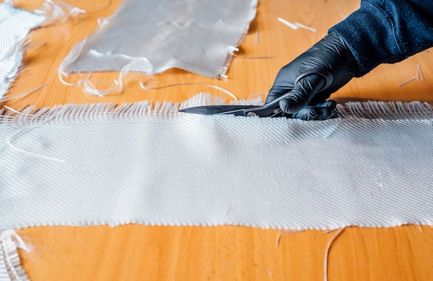 62 year old man cutting fiber with scissors in the workshop.