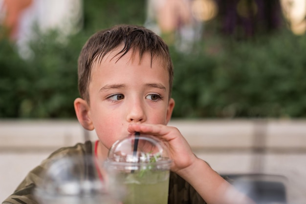 A 6yearold boy is drinking lemonade from a straw does not look into the frame his hair is wet