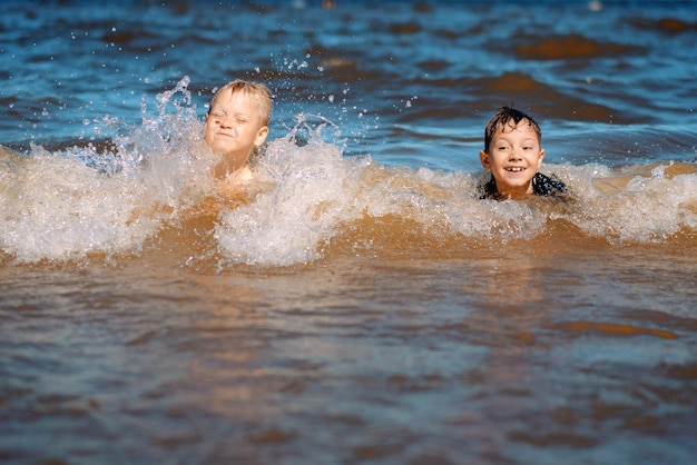 78 years old cute caucasian boys swimming in the sea with big splashes in waves