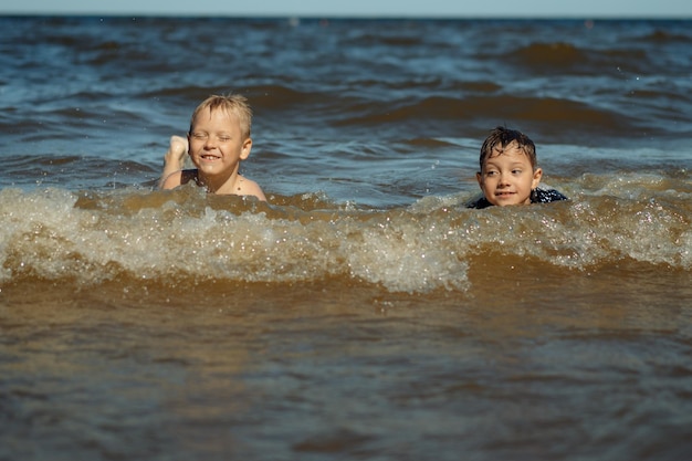 78 years old cute caucasian boys swimming in the sea with big splashes in waves