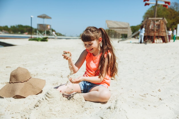 A 7yearold girl plays in the sand on a city beach Vacation and rest Playful active child on the beach in summer vacation