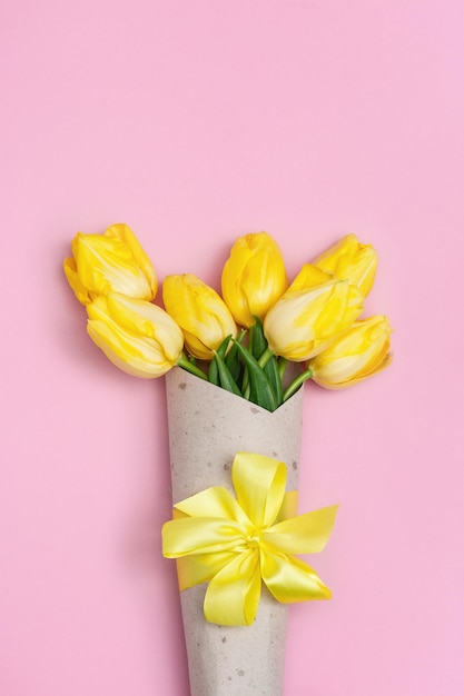 8 March Mother Womens Day concept with yellow tulips flower in paper package with ribbon