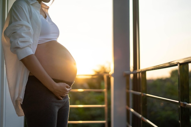 An 8 month pregnant woman gently touches her belly at sunset Mom with baby in abbomen so happy time while she is pregnant