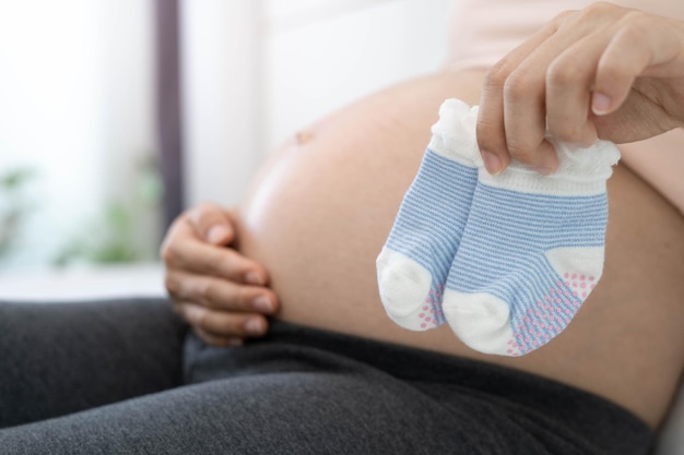 A 8 month pregnant woman is happy to prepare socks for baby Good mother or mom