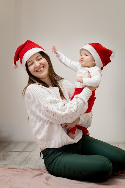 A 9-month-old girl tries to pull a Christmas hat off her mother's head, Mom turns away and laughs