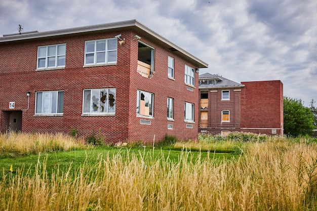 Abandoned brick buildings surrounded by overgrown fields