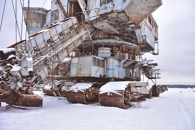 Abandoned giant bucket wheel excavator stands in a field in winter