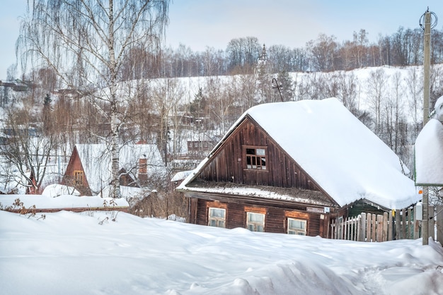 Abandoned old wooden black house in Plyos in the light of a winter day under a blue sky