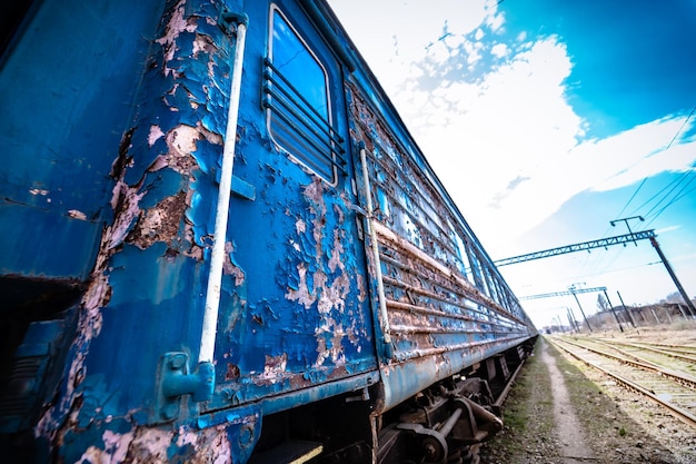 Abandoned railway station Rusty weathered peeled paint of an old wagon Blue railway carriage Wooden sleepers or cross ties