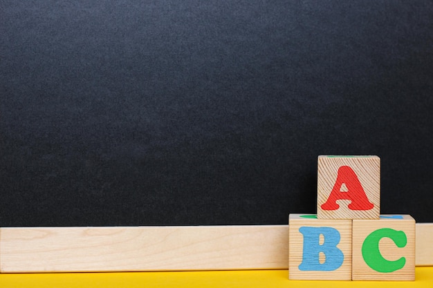 ABC blocks next to a blackboard Back to school English for beginners Empty space for text