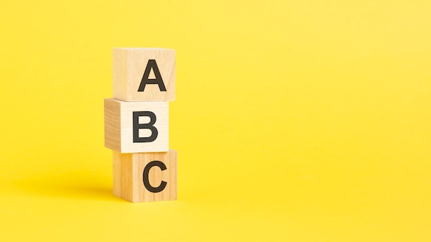 ABC text on wooden cubes on yellow background