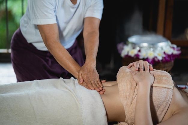 Abdominal massage and spa relaxing treatment of office syndrome traditional thai massage style Asain female masseuse doing massage treat abdomen relax and stress for office woman tired from work