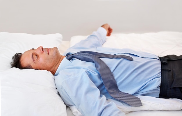 Absolute exhaustion A businessman lying on his bed absolutely exhausted