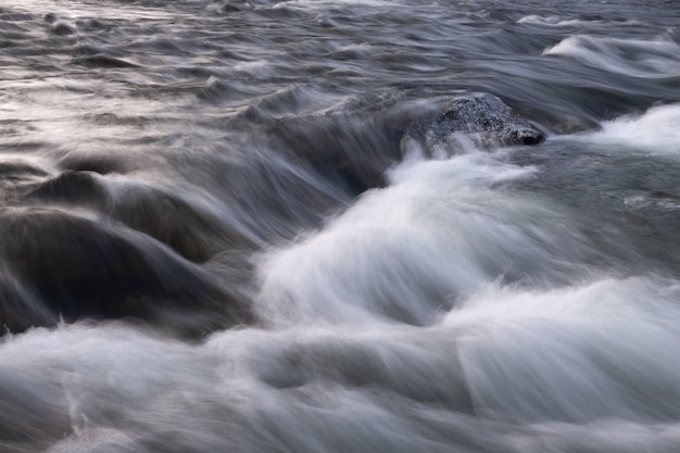 Abstract background from long exposure of water stream in a mountain river close-up