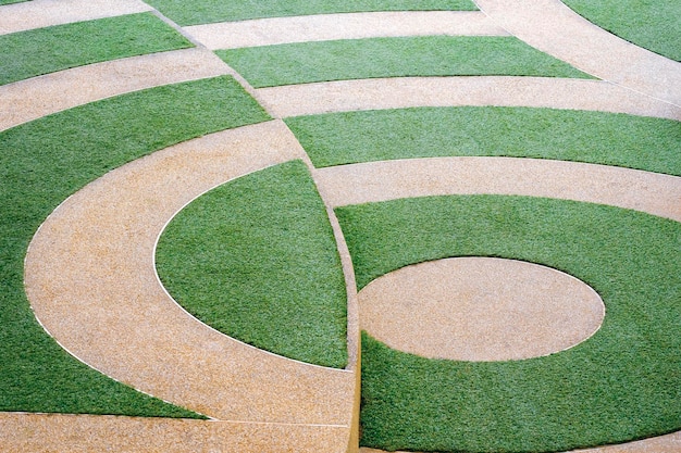 Abstract background of green artificial grass and gravel stone on pavement floor in public park