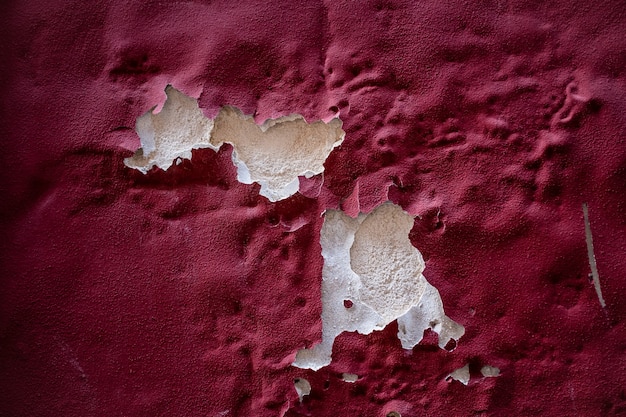 Abstract background of maroon painted surface peeled off due to damp crept