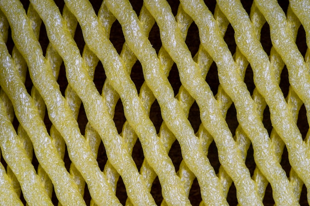 Abstract background of yellow plastic mesh texture for fruit storage close up