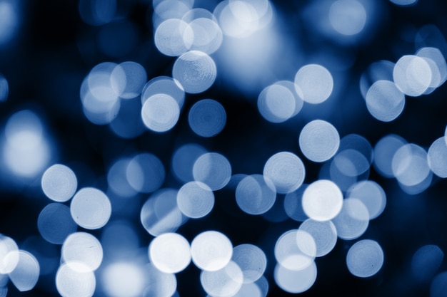 Abstract blue circles bokeh for Christmas of any background, defocused. Soft colorful blurred and glowing lights toned trendy classic blue color of year 2020