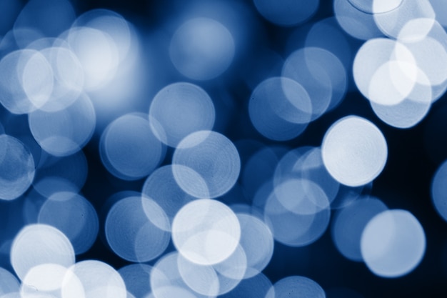 Abstract blue circles bokeh for Christmas of any background, defocused. Soft colorful blurred and glowing lights toned trendy classic blue color of year 2020