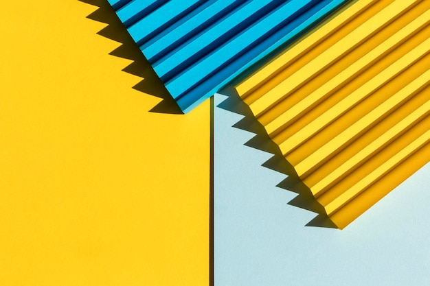 Photo abstract blue and yellow colored paper texture folded paper with harsh sun shadows geometric shapes and lines minimalist background flat lay copy space