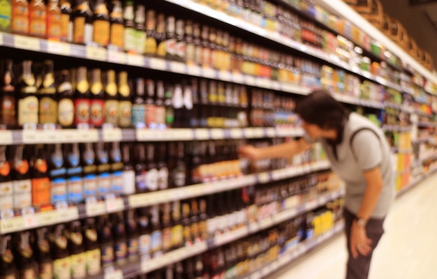 Abstract blurred of a man selecting beer bottles from the grocery shelf