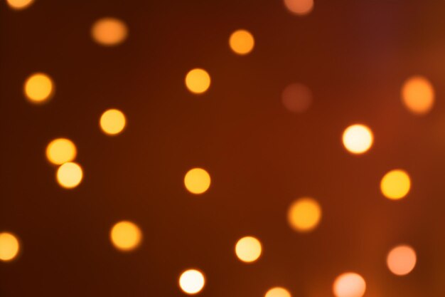 Abstract blurry background with golden bokeh lights on a dark brown background