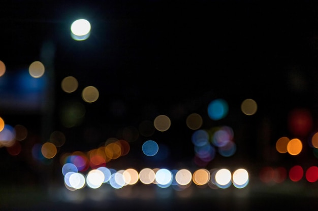 Abstract bokeh background of dark street with light car and street lamps City life defocused lights from cityscape stylish colorful