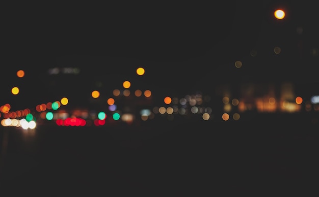 Abstract bokeh background of night street with car and street lamps. City life, defocused lights from cityscape, style color tone. Concept of abstract stylish urban backgrounds for design. Copy space