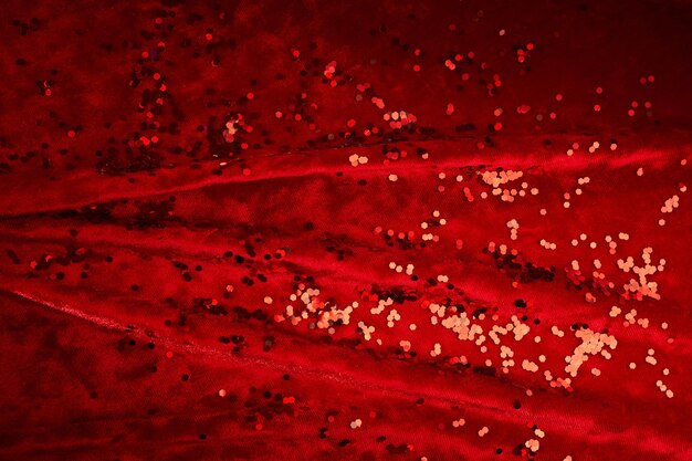 Photo abstract christmas background made of red velvet fabric with red sparkles