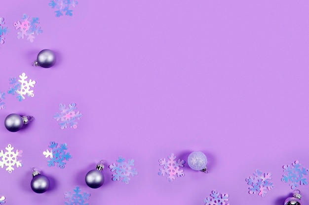 Abstract christmas background in violet violet confetti and christmas balls on a violet background