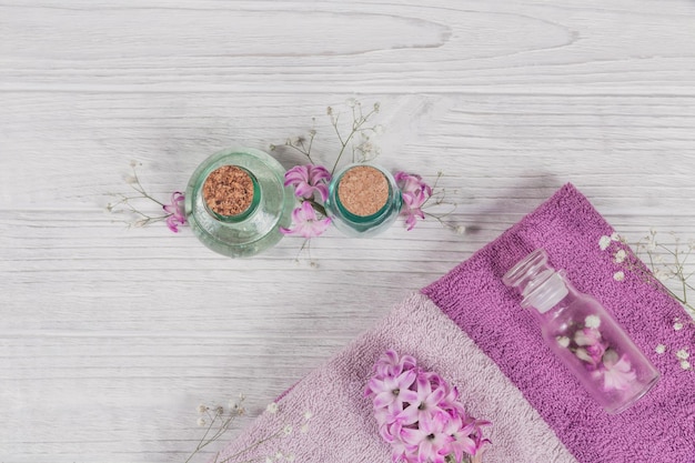 Abstract composition of purple hyacinths flowers towels and bottles of organic cosmetic with essential oil