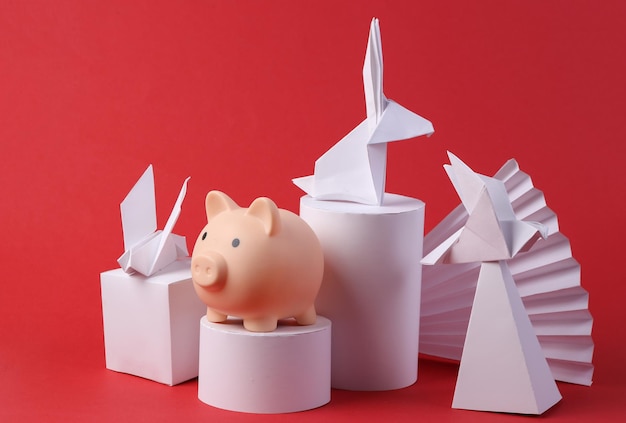 Abstract composition with origami animals piggy bank geometric shapes on a red background