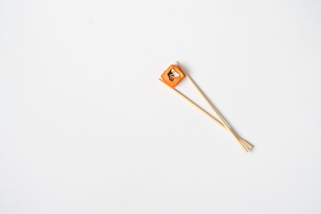 An abstract concept of the asian wooden chopsticks with a roll national food on color surface