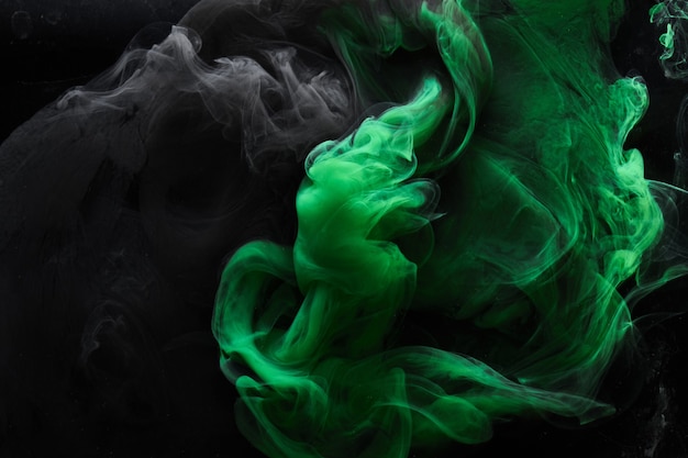 Abstract dance of green and black smoke under water, paint in water, colorful cloud in motion. Fluid art wallpaper, liquid vibrant colors