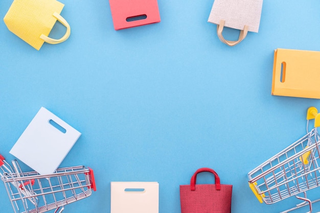 Photo abstract design element concept of annual sale shopping season mini yellow cart with paper bag isolated on pastel blue background top view flat lay