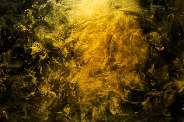 Abstract liquid art, yellow smoke bomb on black background, amber color acrylic paints under water