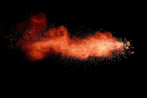 Abstract orange powder explosion on black background. Freeze motion of orange powder splash.