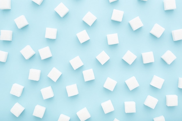 Abstract pattern made of sugar cubes scattered on blue background