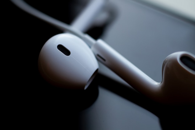 Abstract photo of headphones on the glass of a smartphone close-up. Technology, design and ergonomics.