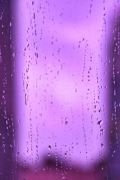 Abstract purple backgrounds with raindrops on blurred daylight Rain drops on window glass for background rainy fall autumn weather