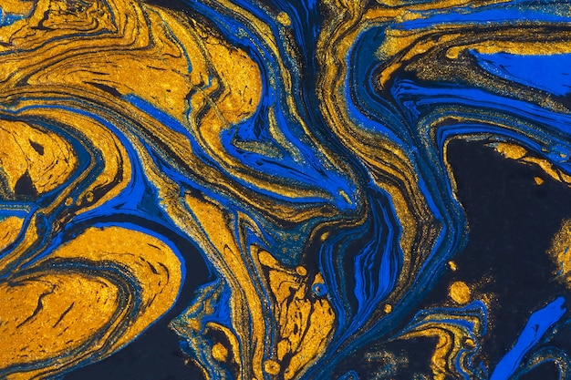 Abstract space blue gold black background. Acrylic painting fluid art. Golden waves of the ocean. Conceptual art drawing. Fashionable background for posters, postcards, invitations. Contemporary art