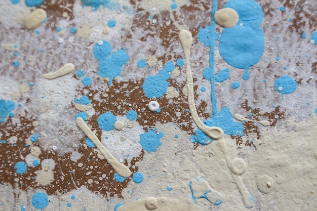 Abstract spots drops of yellow blue white paint on a brown wooden surface