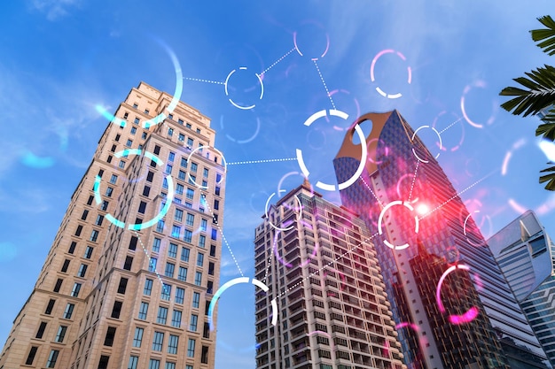 Abstract technology icons hologram on low wide angle view of glass and steel contemporary skyscrapers in financial downtown The concept of success in hitech industry Double exposure