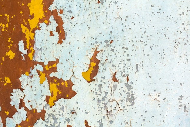 Abstract texture of vertical grungy rusting metal plate with peeling paint and extensive corrosion with rust streaks.