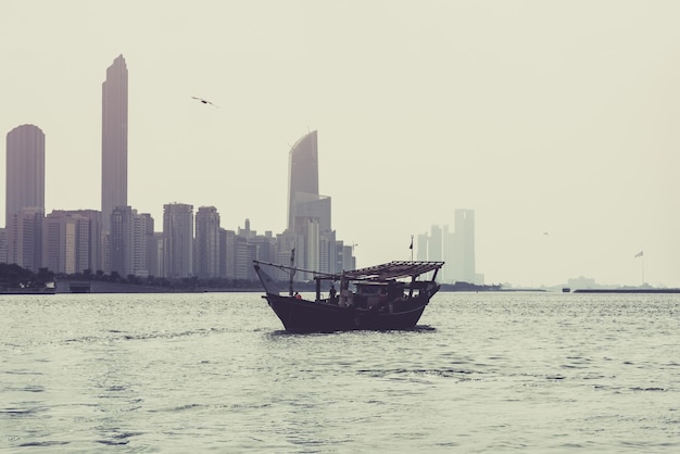 Abu Dhabi buildings skyline with old fishing boat on the front